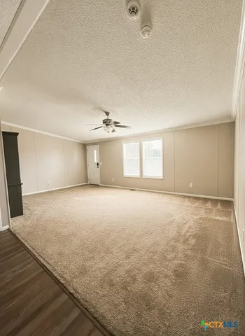 an empty room with chandelier fan and windows