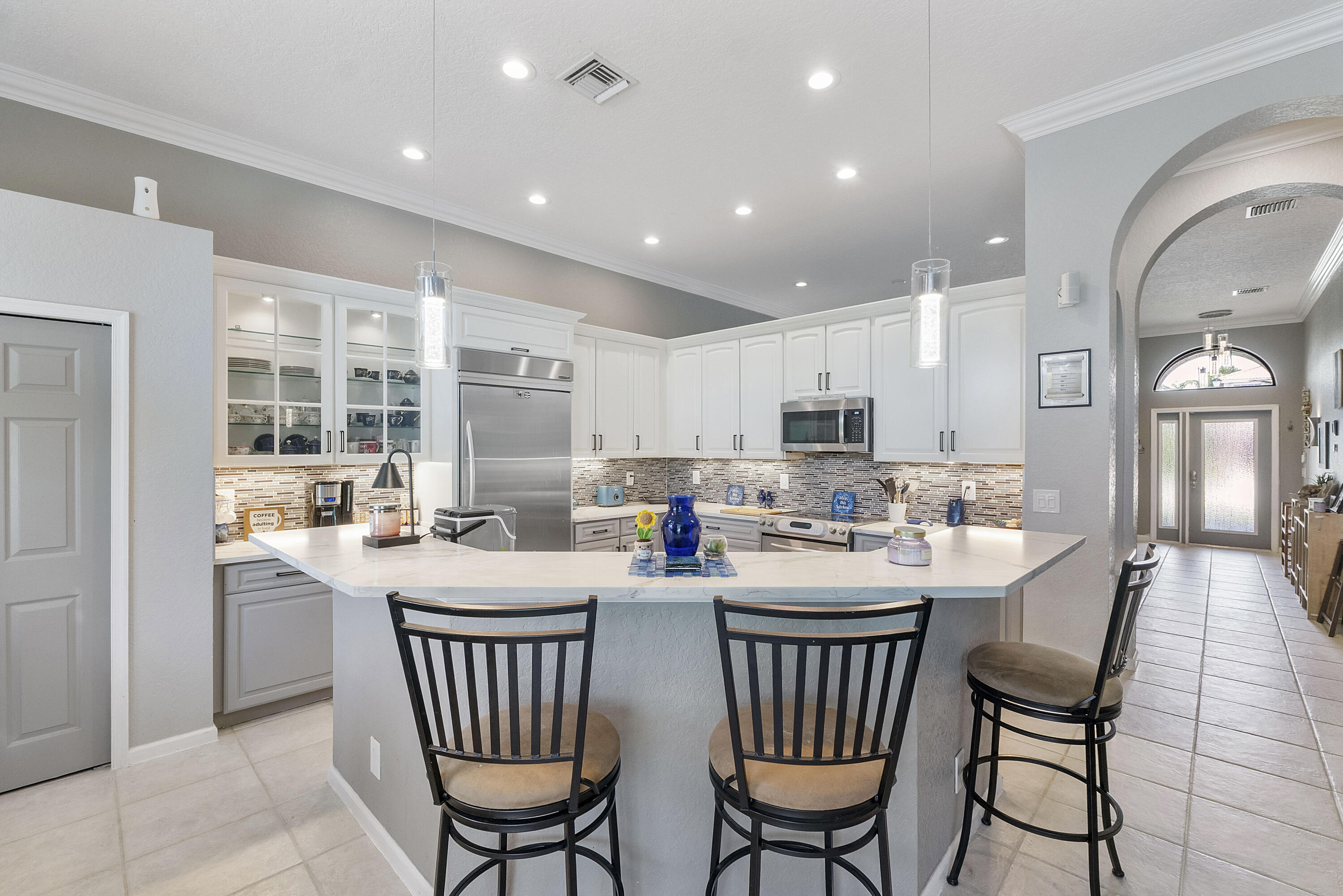 12328 St Simon Drive Boca Raton, FL 33428 - Photo 15 of 52 a kitchen with a dining table chairs and refrigerator
