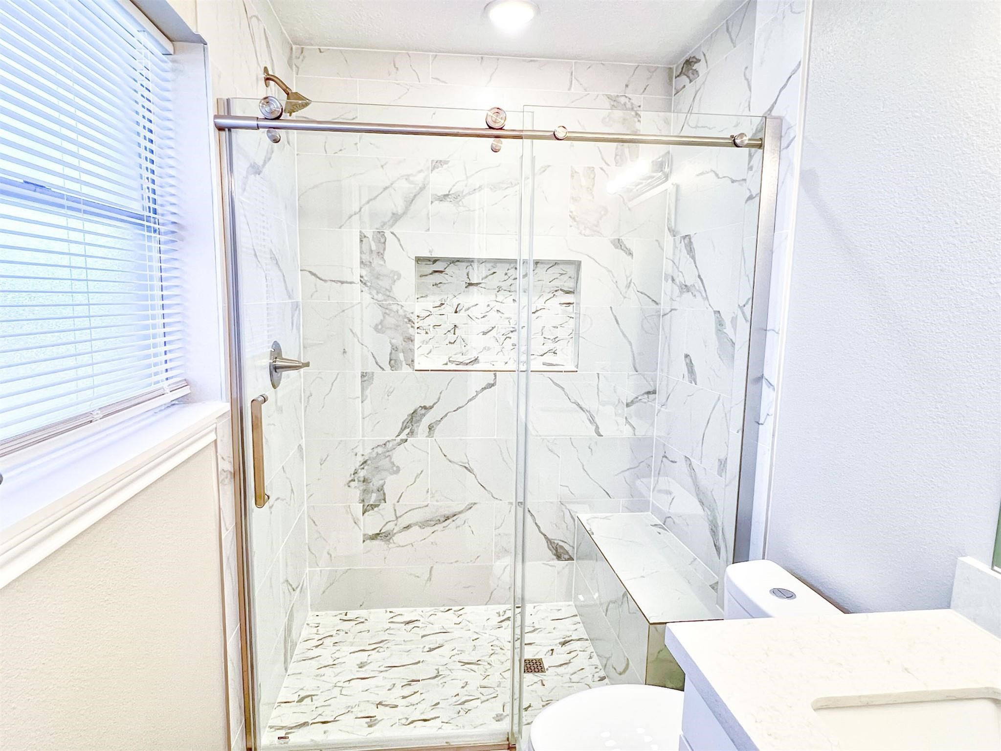 415 Sevenhampton Lane Houston, TX 77015 - Photo 15 of 28 Stunning tiled shower with bench seat in the primary bathroom
