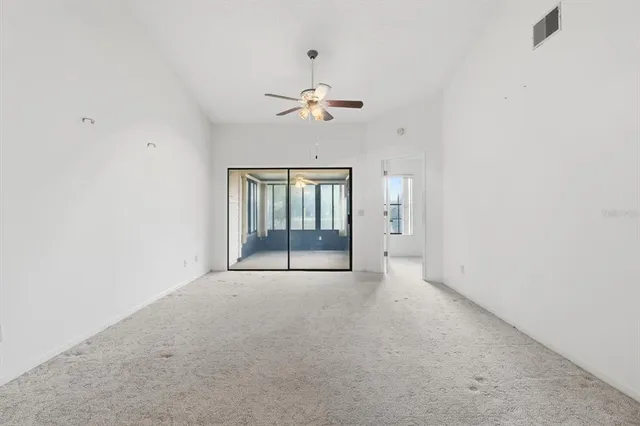 an empty room with chandelier fan and windows