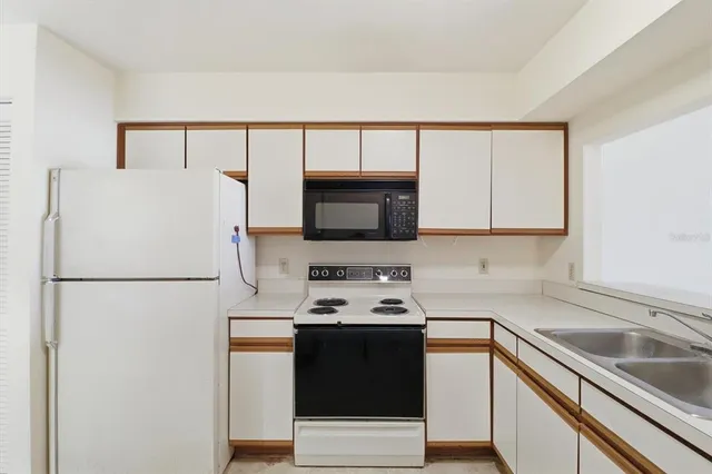 a white kitchen with stainless steel appliances a refrigerator sink and cabinets