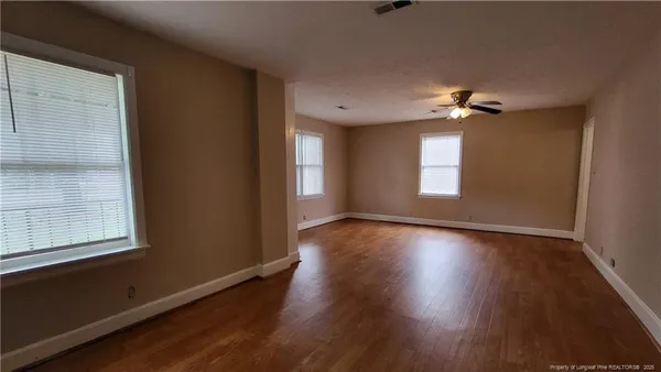 an empty room with wooden floor and windows