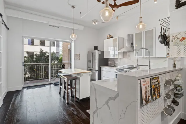 a kitchen with stainless steel appliances kitchen island granite countertop a stove a sink a refrigerator and white cabinets with wooden floor