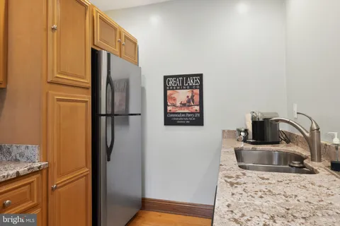 a kitchen with stainless steel appliances granite countertop a stove top oven a sink a dining table and chairs with wooden floor