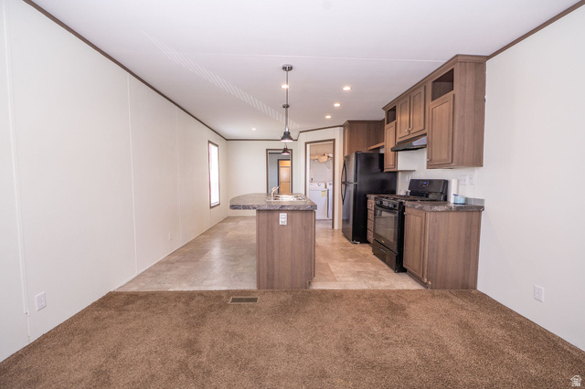 2491 Highway 89, Unit 403 Pleasant View, UT 84404 - Photo 8 of 32 Open-concept living space featuring a kitchen with black appliances, wood-finish cabinetry, and a peninsula with a sink and pendant lighting
