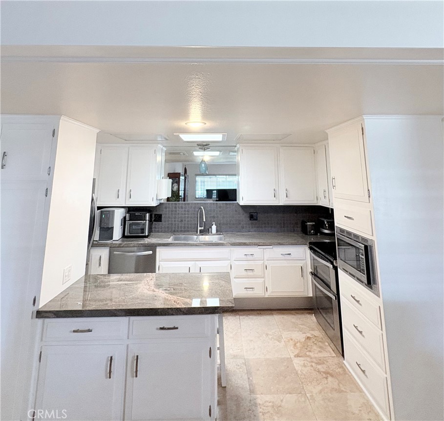 1680 Monterey Road Seal Beach, CA 90740 - Photo 9 of 19 a large kitchen with granite countertop a stove a sink a refrigerator and white cabinets with wooden floor