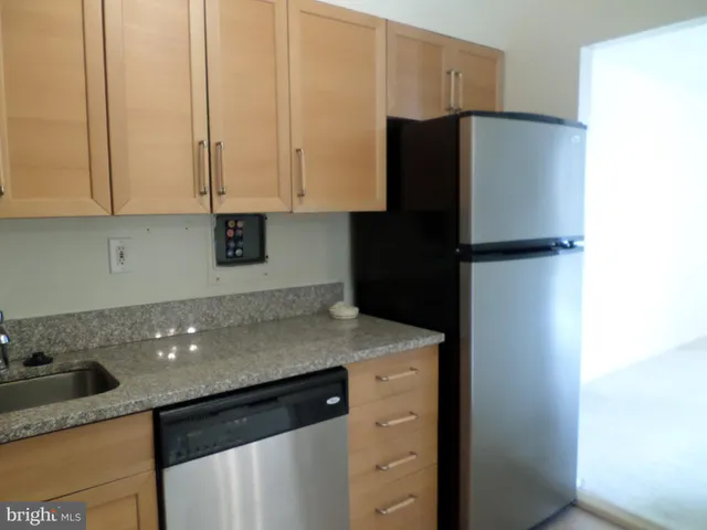 a kitchen with stainless steel appliances granite countertop a refrigerator a sink and white cabinets