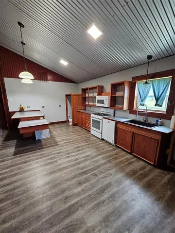 a kitchen with stainless steel appliances kitchen island granite countertop a sink cabinets and wooden floor