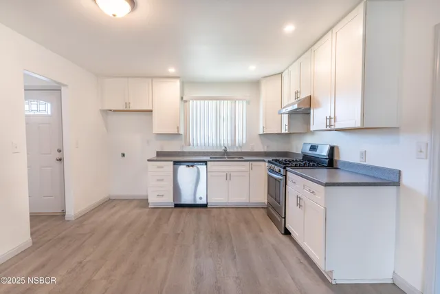 a kitchen with granite countertop white cabinets and white stainless steel appliances