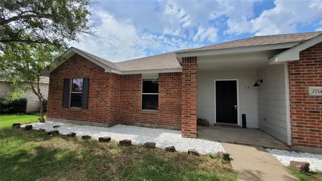 a brick house with tree in front of it