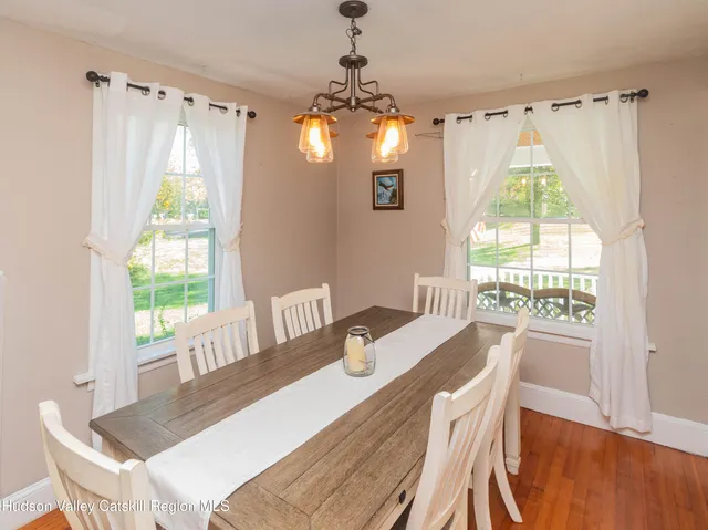 a dining room with wooden floor a chandelier a wooden table and chairs