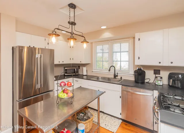a kitchen with stainless steel appliances granite countertop a sink a stove a refrigerator cabinets and a dining table