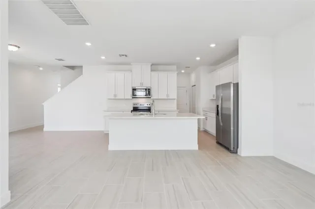 a large kitchen with stainless steel appliances refrigerator sink and cabinets