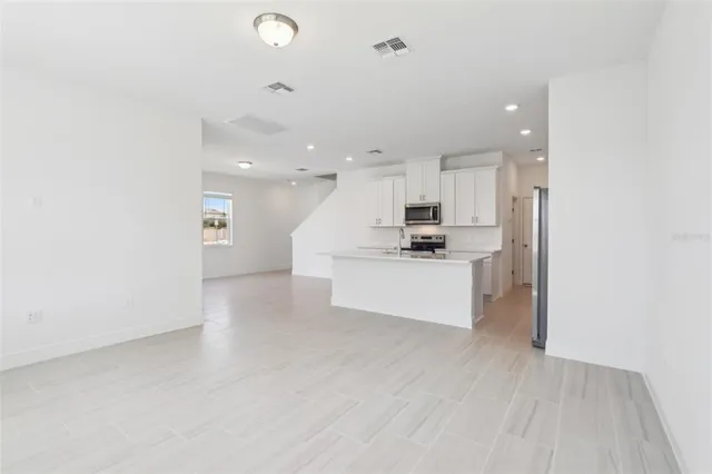 a view of kitchen with kitchen island white cabinets and stainless steel appliances