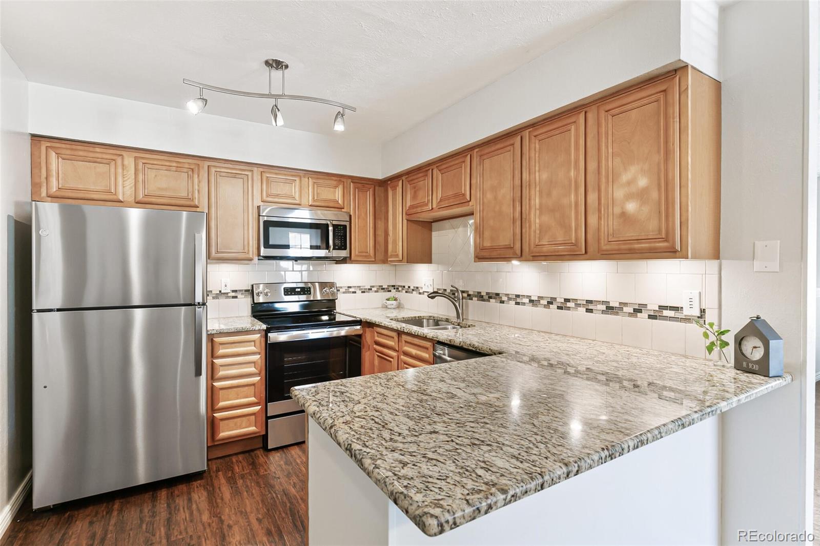 8417 Everett Way, Unit C Arvada, CO 80005 - Photo 16 of 34 a kitchen with a refrigerator a microwave a sink and wooden floor