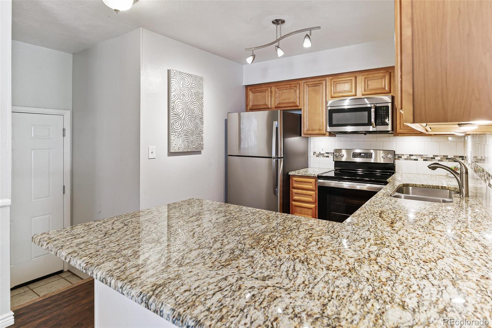 8417 Everett Way, Unit C Arvada, CO 80005 - Photo 17 of 34 a kitchen with stainless steel appliances granite countertop a refrigerator sink and stove