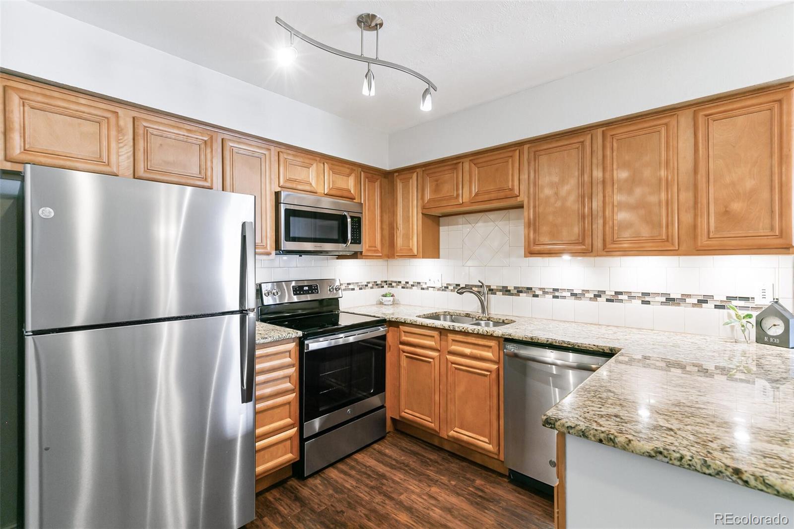 8417 Everett Way, Unit C Arvada, CO 80005 - Photo 18 of 34 a kitchen with stainless steel appliances granite countertop a refrigerator a sink dishwasher a stove top oven a refrigerator with island and chairs