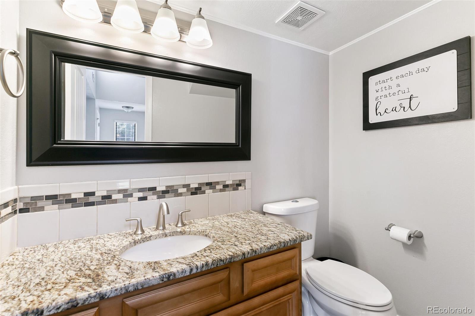 8417 Everett Way, Unit C Arvada, CO 80005 - Photo 21 of 34 a bathroom with a granite countertop toilet sink and mirror