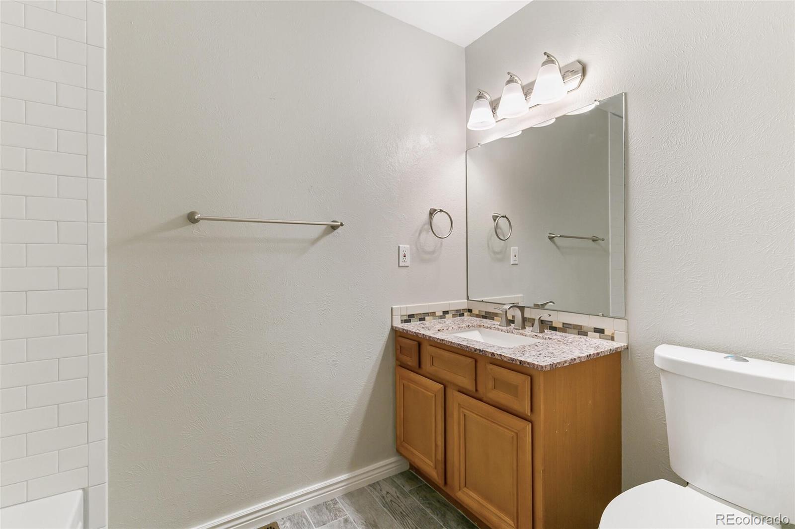8417 Everett Way, Unit C Arvada, CO 80005 - Photo 29 of 34 a bathroom with a sink a toilet and mirror