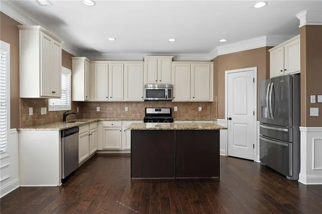 a kitchen with granite countertop white cabinets and stainless steel appliances