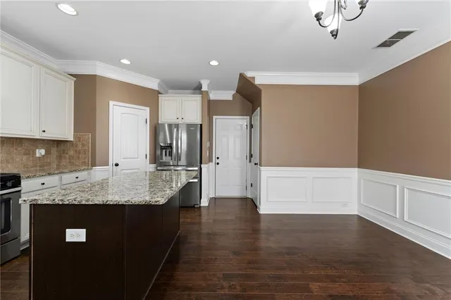 a large kitchen with stainless steel appliances granite countertop a lot of counter space and wooden floors