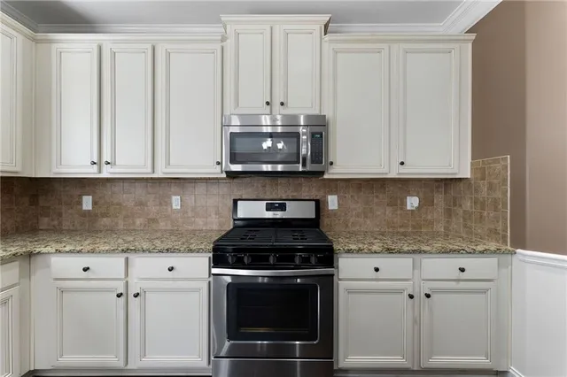 a kitchen with stainless steel appliances granite countertop white cabinets and a stove