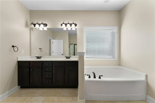 a bathroom with a tub a double vanity sink and a window