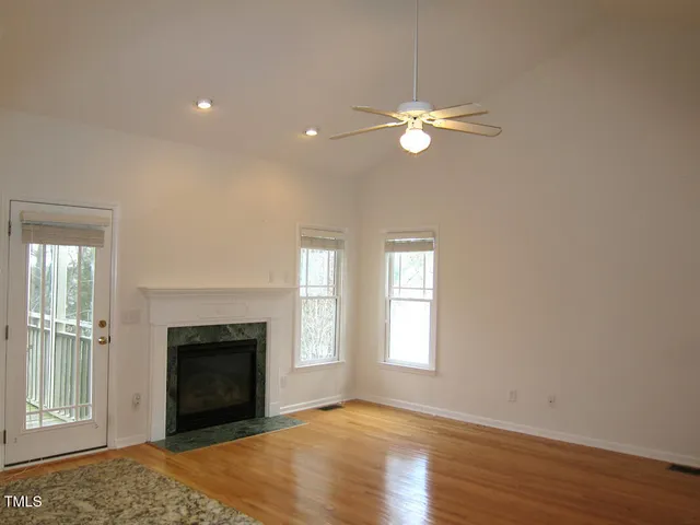 an empty room with windows fireplace and wooden floor