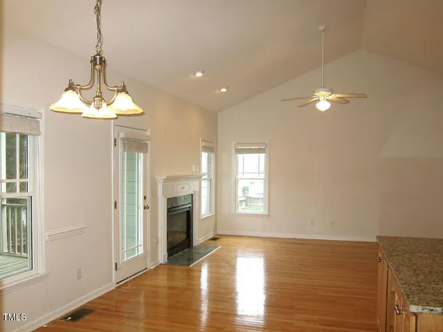 a view of a livingroom with a chandelier a fireplace wooden floor and windows
