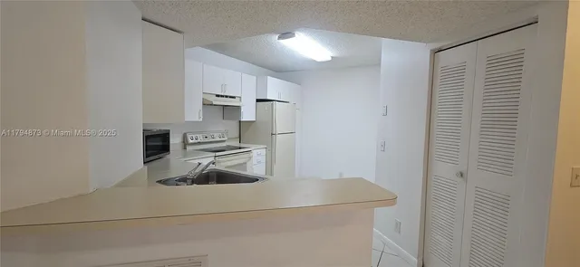 a kitchen with white cabinets and white appliances