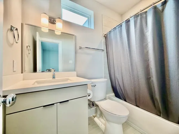 a bathroom with a sink a toilet a mirror and shower curtain