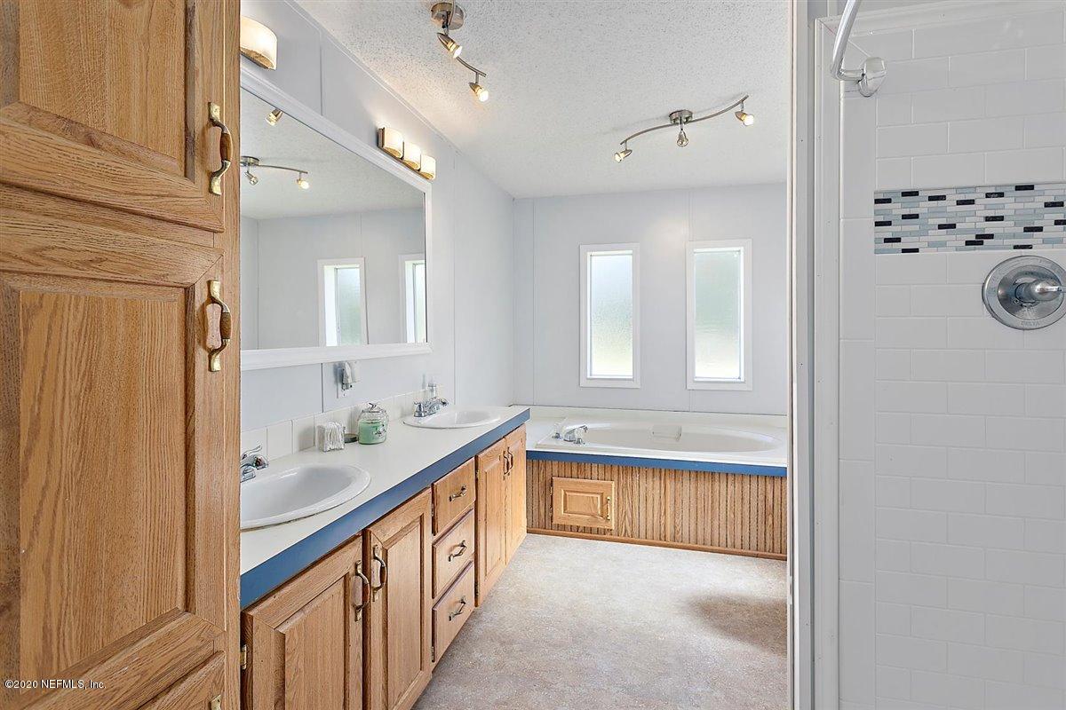 2987 Green Acres Road St. Augustine, FL 32084 - Photo 16 of 31 a bathroom with a sink a mirror and a bathtub next to a window