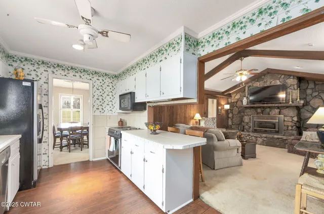 a open kitchen with stainless steel appliances granite countertop a stove top oven a sink a dining table and chairs with wooden floor