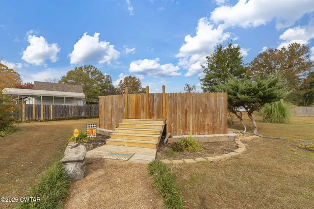 a view of backyard with a huge green area and wooden fence