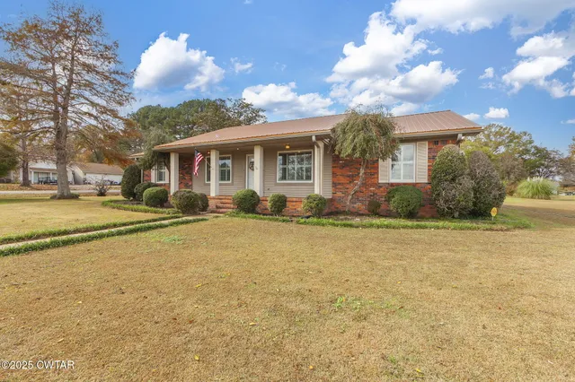 a front view of house with yard and trees around