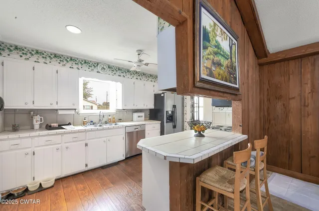 a kitchen with granite countertop a sink and white cabinets with wooden floor