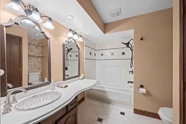 a bathroom with a granite countertop sink mirror vanity and toilet
