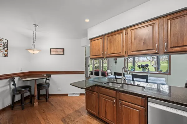 a kitchen with stainless steel appliances granite countertop sink window and table chairs