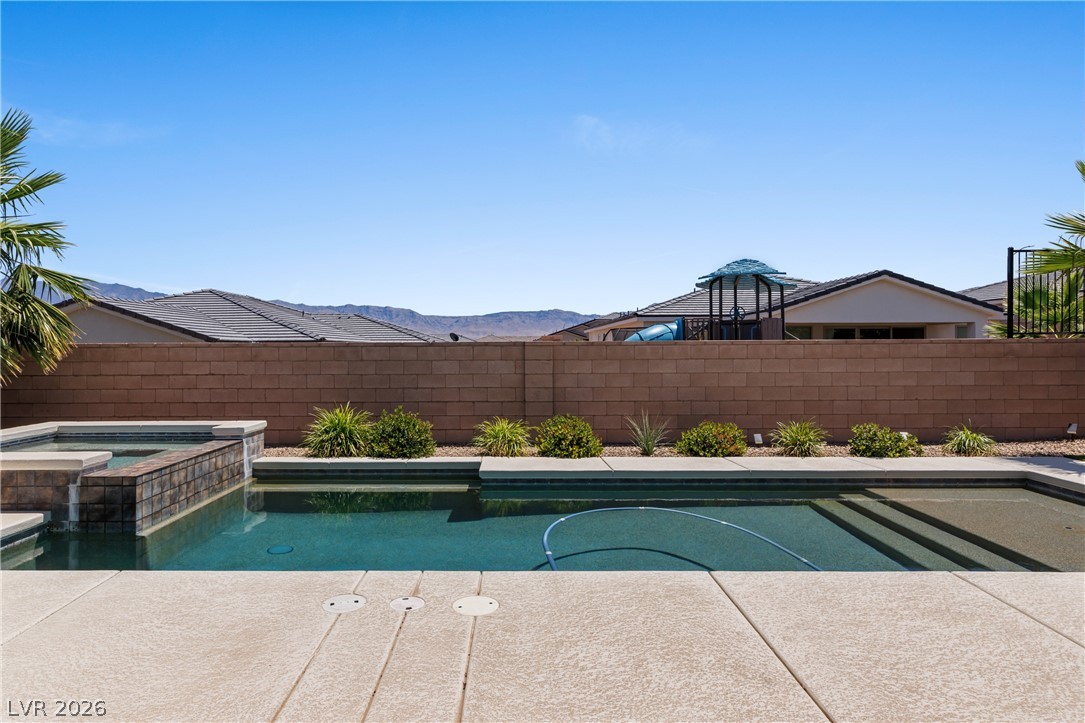 1436 Manassas Ridge Mesquite, NV 89027 - Photo 60 of 77 An inviting backyard oasis offers a sparkling pool with an integrated spa, set against distant mountains.