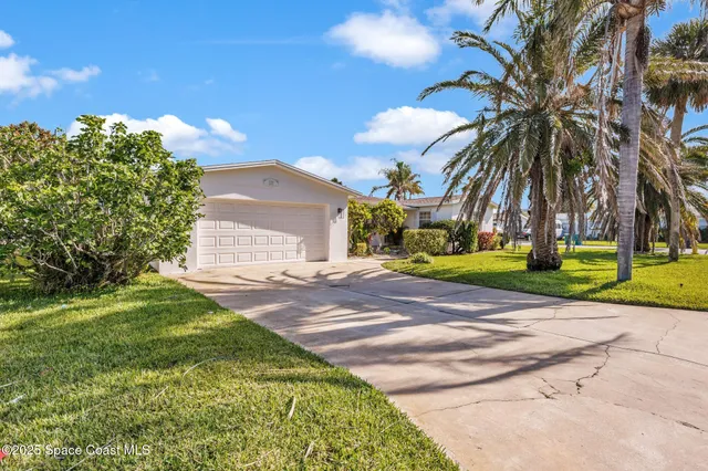 a view of a house with a yard and coconut trees