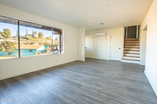 a view of an empty room with a window and wooden floor