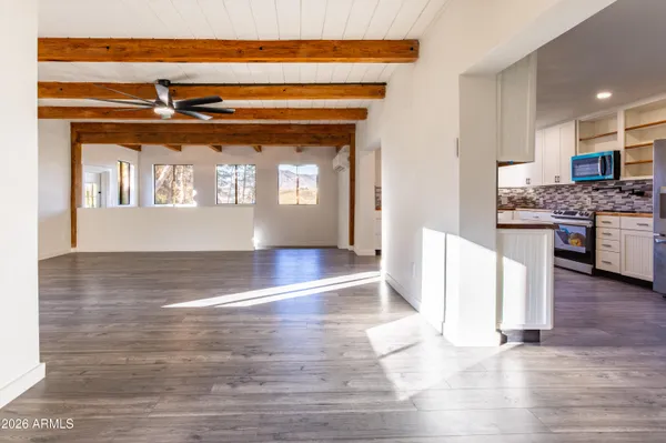 a view of a refrigerator in a hall with wooden floor and a living room