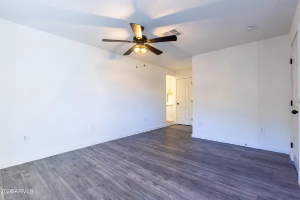 an empty room with wooden floor fan and windows