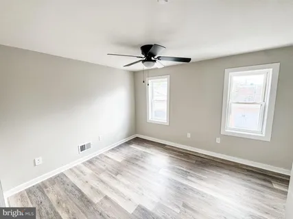 a view of an empty room with window and wooden floor