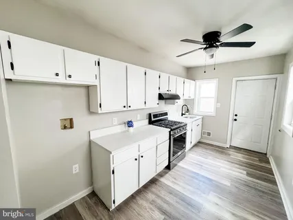 a kitchen with a white cabinets and wooden floor