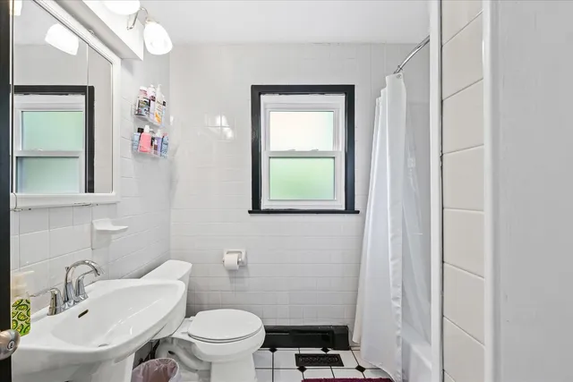 a bathroom with a toilet a sink a mirror and a window