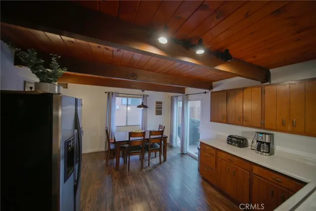 a kitchen with stainless steel appliances granite countertop a refrigerator a sink dishwasher a stove and a dining table with wooden floor