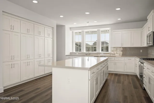 a large kitchen with granite countertop a sink and dishwasher a stove top oven with wooden floor