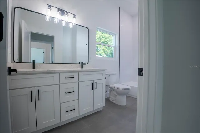 a bathroom with a granite countertop toilet sink and mirror