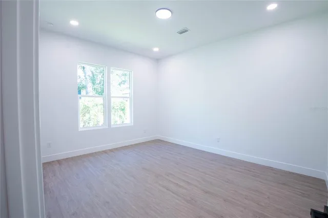 an empty room with wooden floor and windows